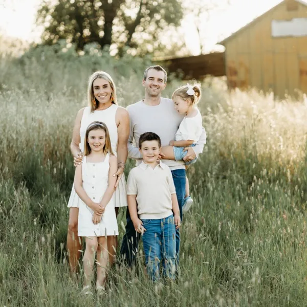 Justine with her husband and their three kids, standing in a field of tall grass.